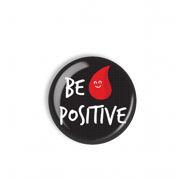 A black button with a red smiley face and the text "BE POSITIVE" printed on it.