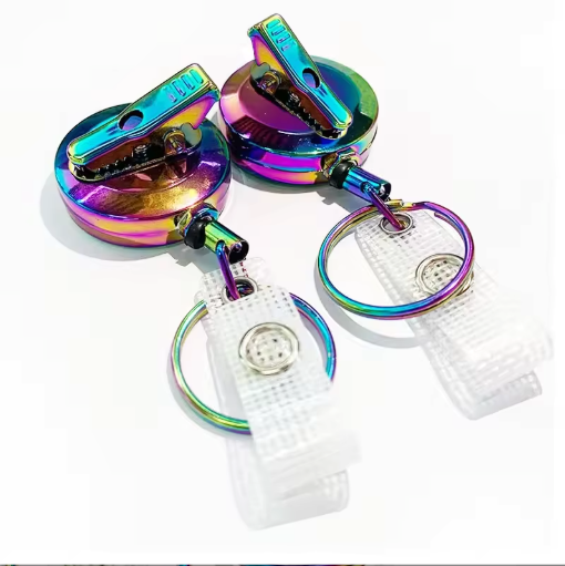 a pair of colorful, rainbow-colored clip-on badges with metal clasps and clear plastic rings.