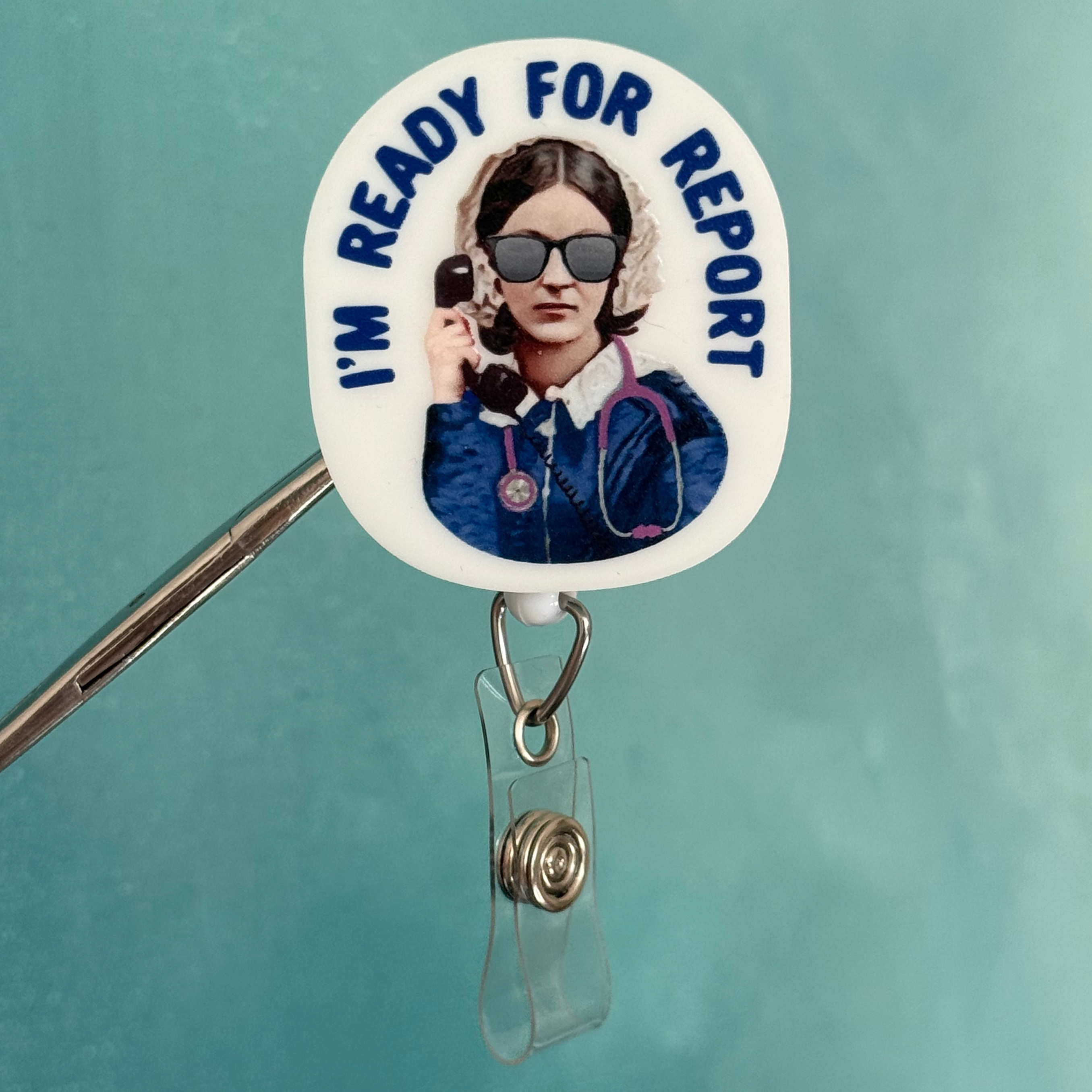 Badge holder with a round badge featuring a person and 'I'm Ready for Report' text on a teal background.
