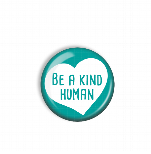 A teal-colored button with a white heart and the text "Be a kind human" printed on it.