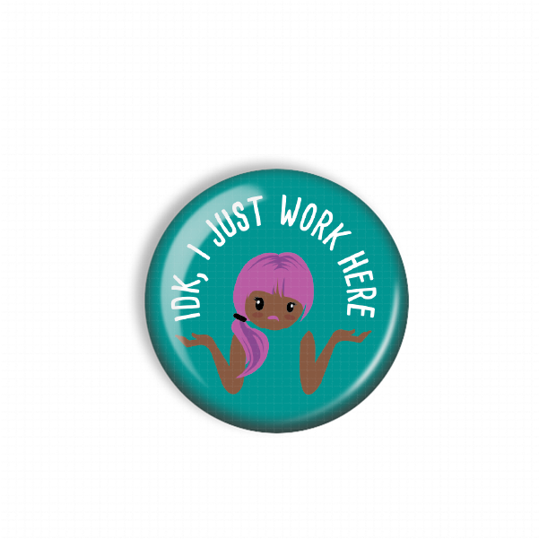 A turquoise button with a cartoon character and the text "IDK, JUST WORK HERE" printed on it.