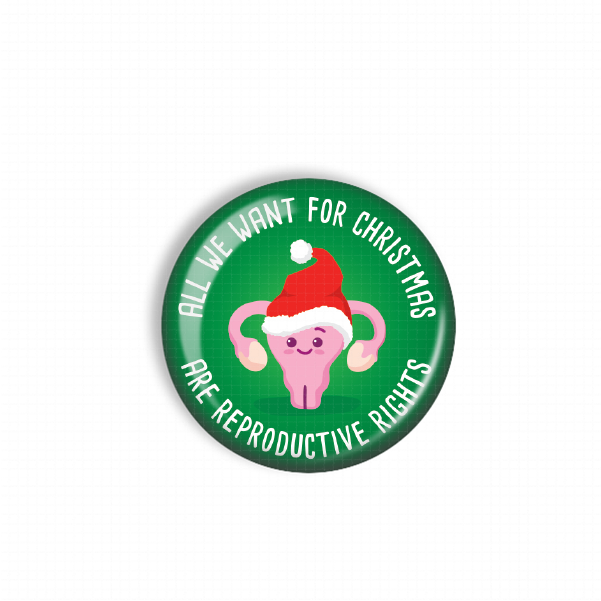 A green button with a pink cartoon character wearing a Santa hat and the text "All we want for Christmas are reproductive rights" printed on it.