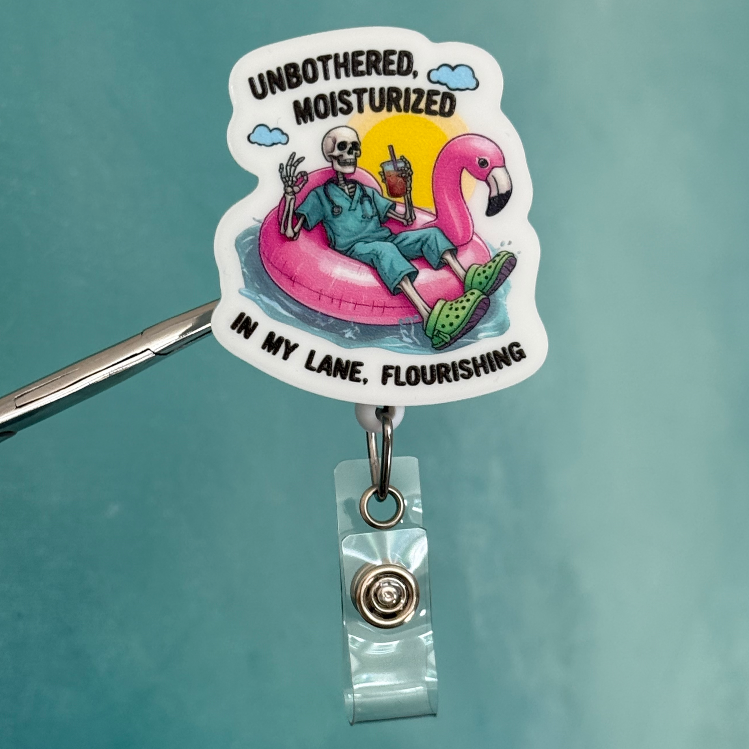 Badge holder with a colorful design featuring two people on a flamingo, text, and a blue background.