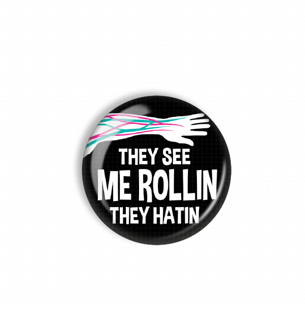 A black and white button with the text "They see me rollin, they hatin" printed on it.