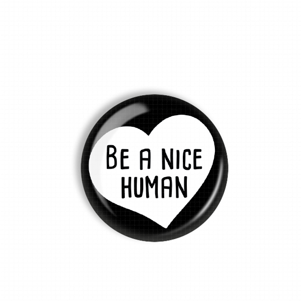A black and white heart-shaped button with the text "BE A NICE HUMAN" printed on it.